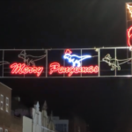 An illuminated sign featuring dinosaurs and the text 'Merry Pengemas'